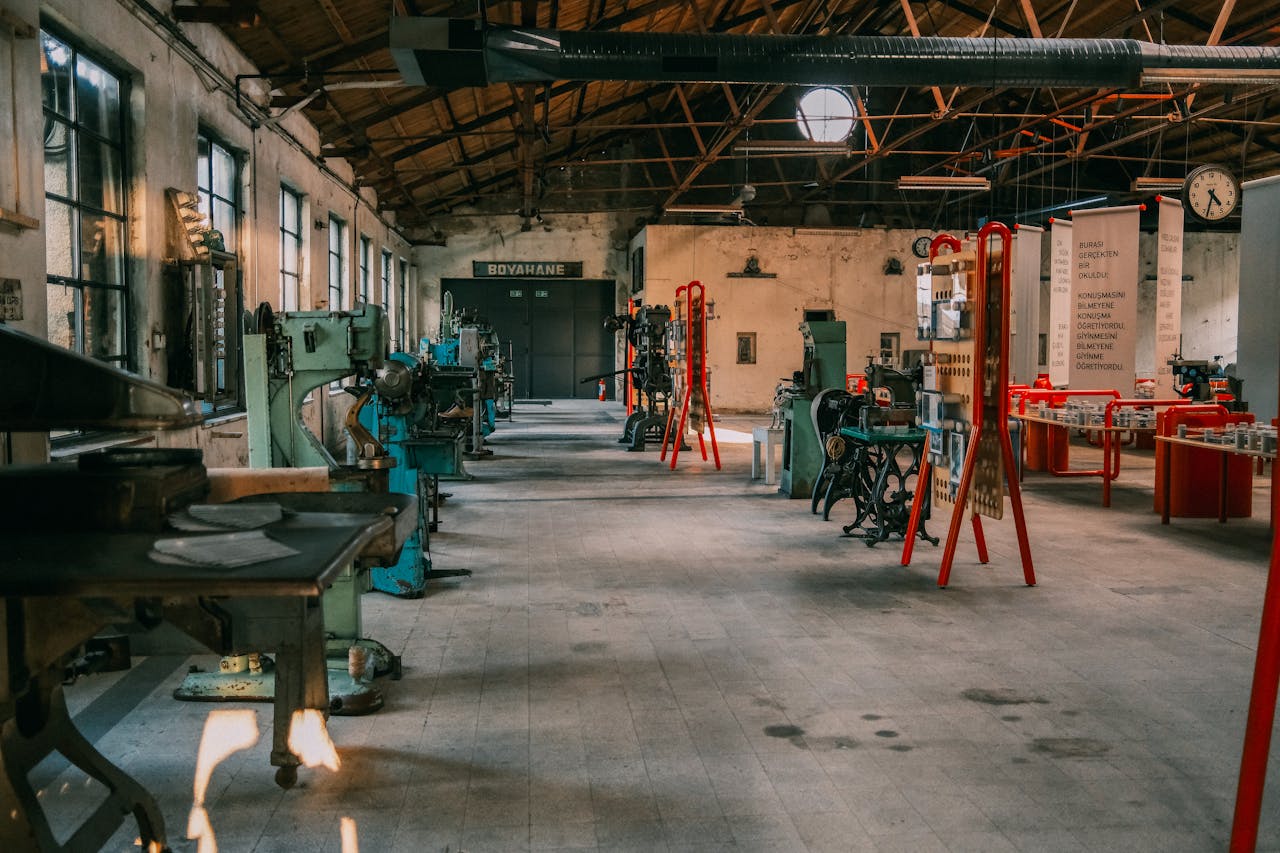 An expansive industrial workshop featuring vintage machinery and tools under a wooden roof.