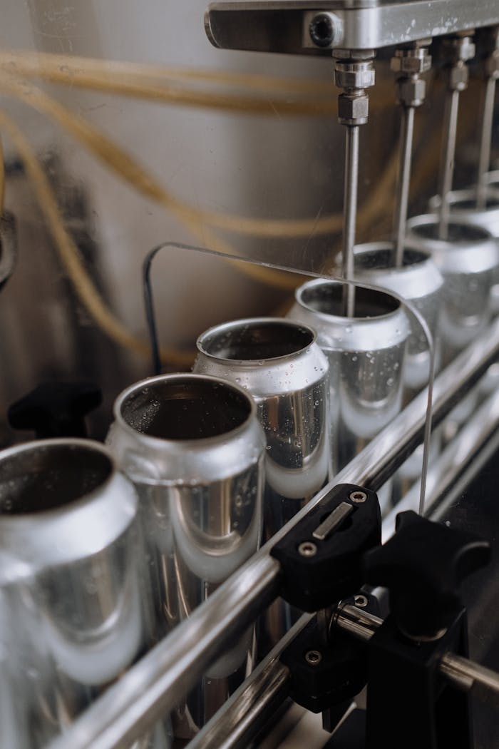 Close-up view of an automated can filling line in a brewery showcasing aluminum cans and machinery.